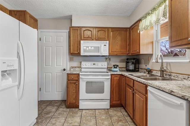 kitchen with brown cabinets, light tile patterned floors, light countertops, a sink, and white appliances