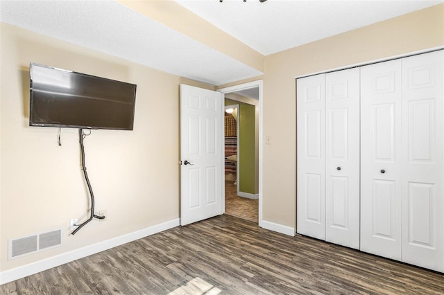 unfurnished bedroom with baseboards, a closet, visible vents, and wood finished floors