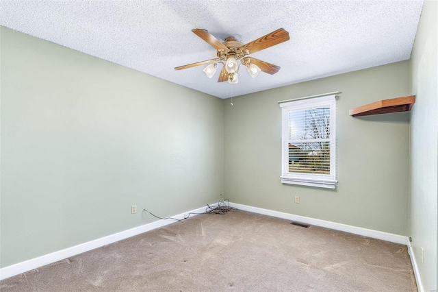 carpeted empty room featuring a textured ceiling, ceiling fan, and baseboards