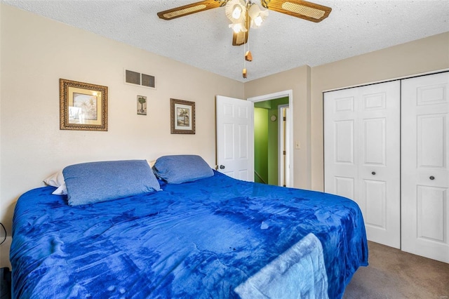 bedroom with ceiling fan, a textured ceiling, carpet floors, visible vents, and a closet