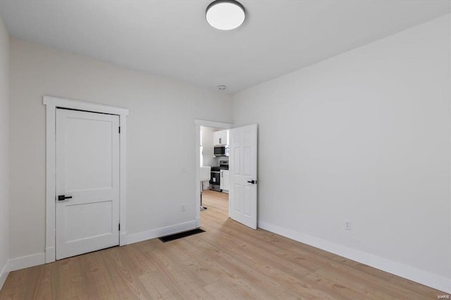 unfurnished bedroom with visible vents, light wood-style flooring, and baseboards