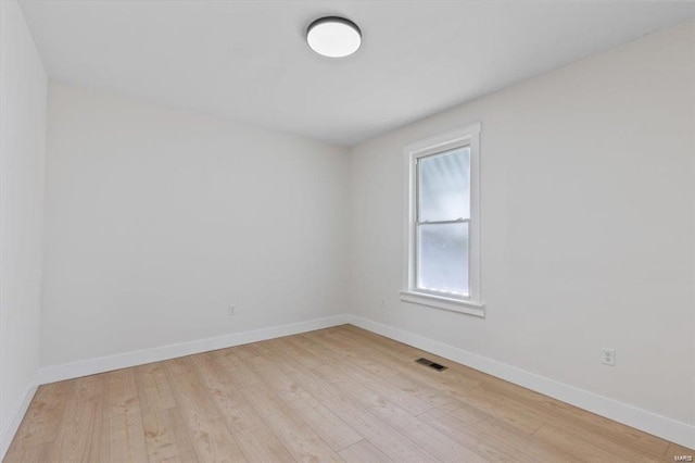 spare room with light wood finished floors, baseboards, and visible vents