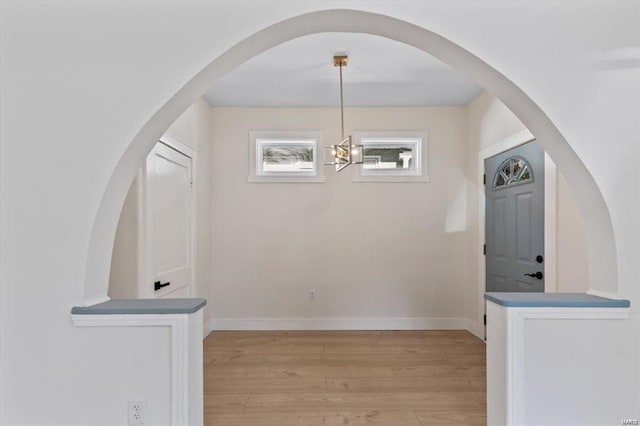 unfurnished dining area with light wood-type flooring and baseboards