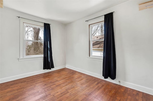 empty room with wood finished floors, baseboards, and a healthy amount of sunlight