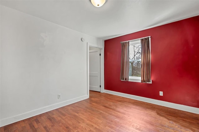 unfurnished room with baseboards and wood finished floors