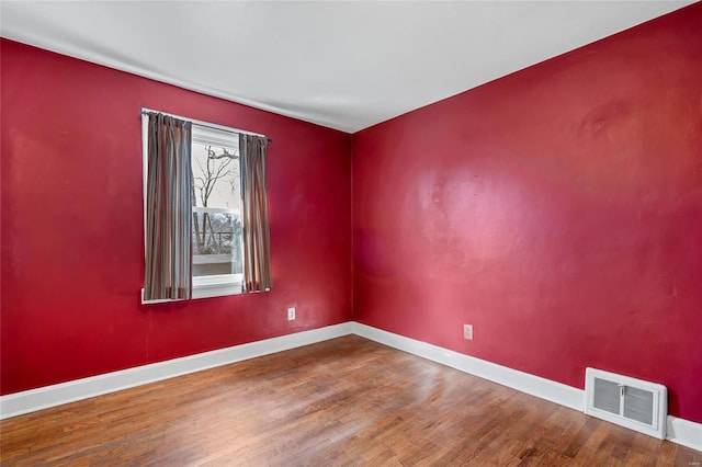 spare room featuring wood finished floors, visible vents, and baseboards