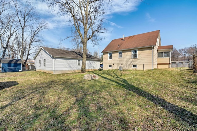 rear view of property featuring cooling unit, a lawn, and fence