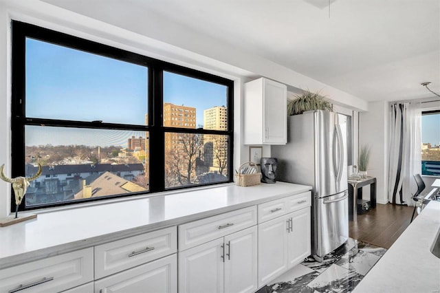 kitchen with white cabinetry, light countertops, freestanding refrigerator, marble finish floor, and a view of city