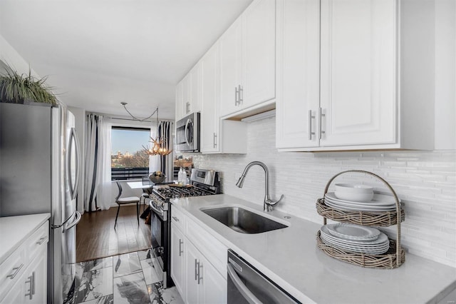 kitchen featuring white cabinets, appliances with stainless steel finishes, light countertops, and a sink