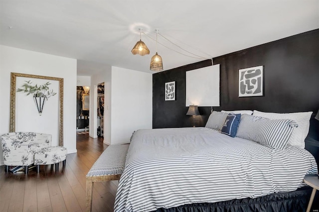 bedroom with an accent wall, baseboards, and wood-type flooring