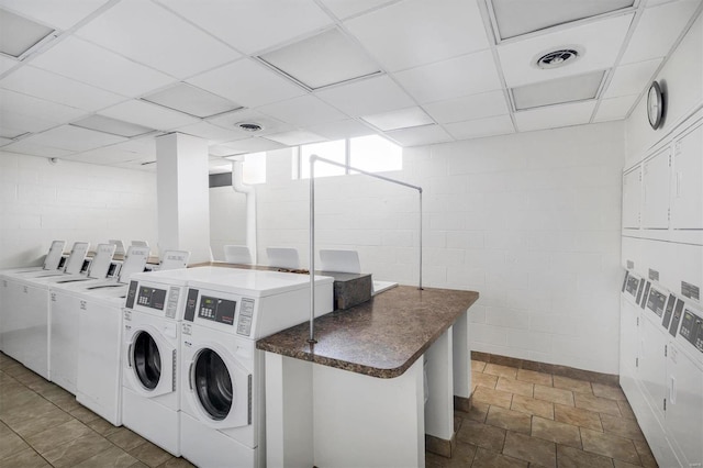 common laundry area with visible vents, separate washer and dryer, concrete block wall, and stacked washer / dryer