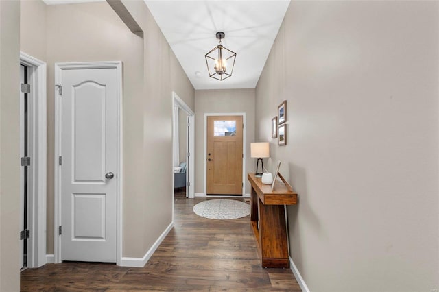 entrance foyer with dark wood-style flooring, an inviting chandelier, and baseboards