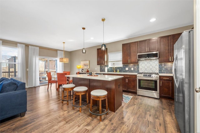 kitchen featuring dark wood-style floors, appliances with stainless steel finishes, a breakfast bar, light countertops, and a sink