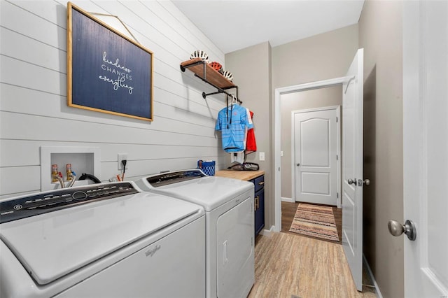 clothes washing area with laundry area, light wood-style flooring, baseboards, and separate washer and dryer