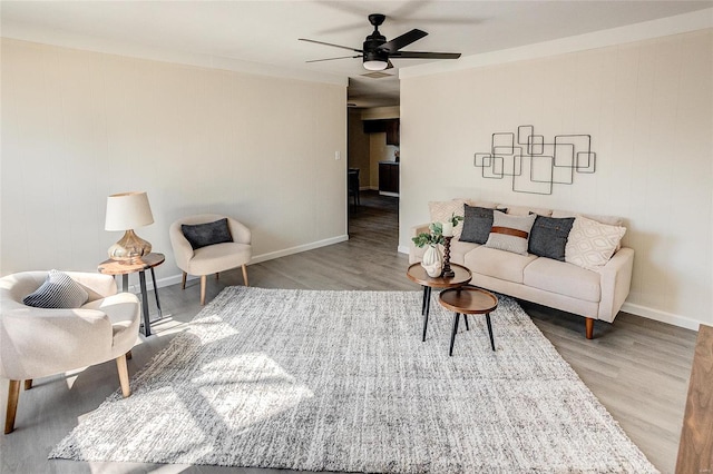 living room with ceiling fan, baseboards, and wood finished floors