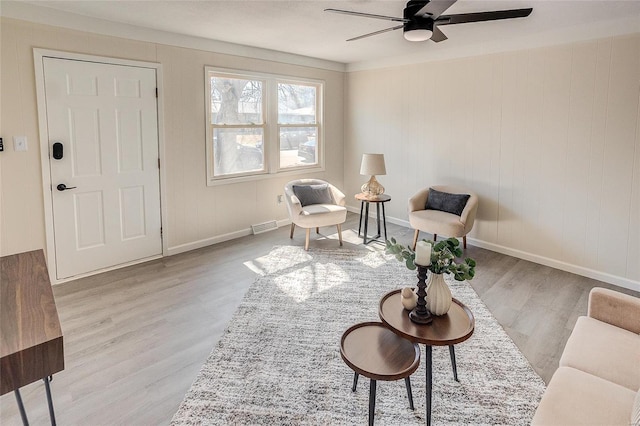 living area with visible vents, baseboards, ceiling fan, and wood finished floors