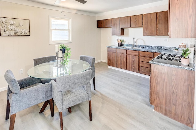 kitchen with a sink, a ceiling fan, light wood-style flooring, and brown cabinetry