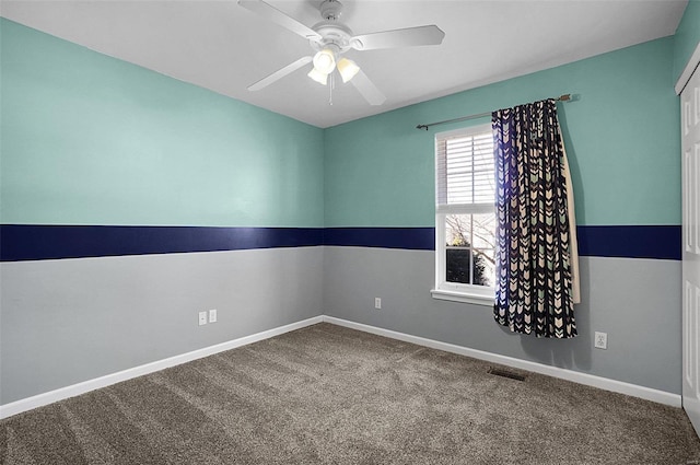 empty room with visible vents, carpet flooring, a ceiling fan, and baseboards