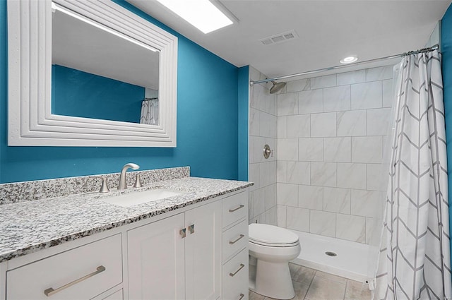 bathroom with vanity, toilet, visible vents, and a tile shower