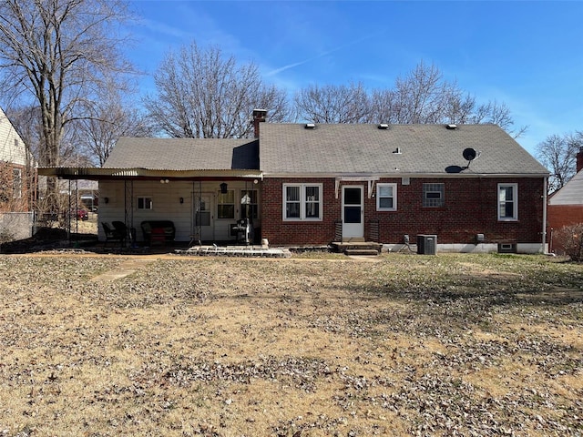 back of property with entry steps, a chimney, central AC, and brick siding