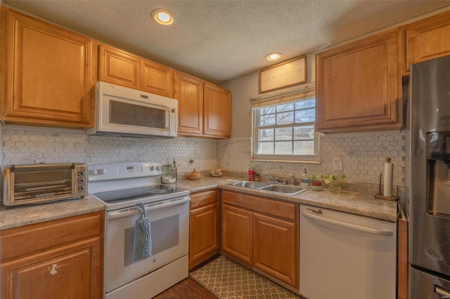 kitchen with a toaster, white appliances, a sink, light countertops, and decorative backsplash