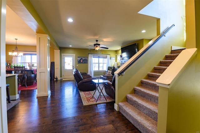 living area with stairway, a healthy amount of sunlight, dark wood-style flooring, and ornate columns