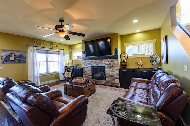 living room with a stone fireplace, recessed lighting, baseboards, and a ceiling fan