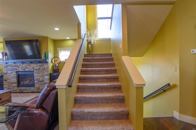 stairs featuring a stone fireplace, recessed lighting, wood finished floors, and baseboards