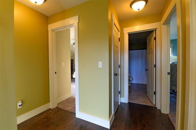 hallway featuring baseboards and dark wood-style floors