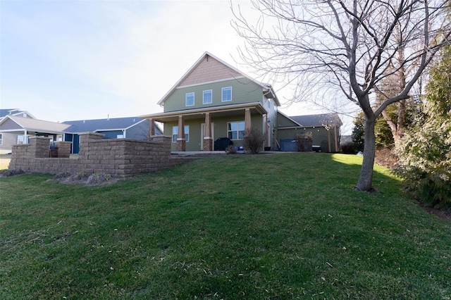 rear view of property featuring a porch, a lawn, and fence