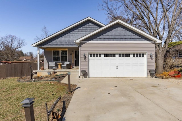 view of front of property featuring driveway, covered porch, an attached garage, and fence