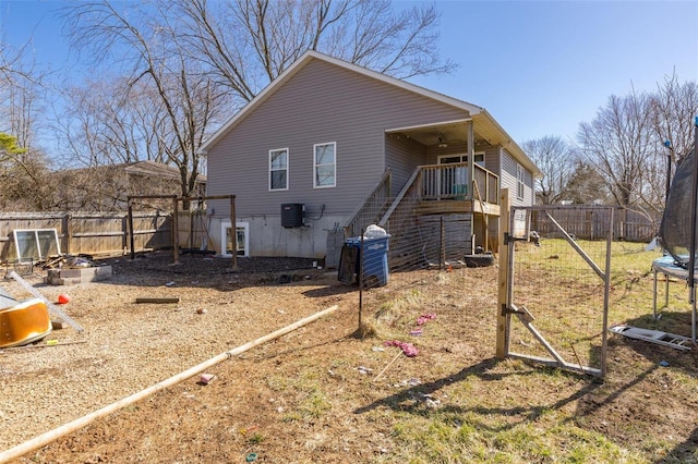 back of house featuring stairs, a trampoline, central AC unit, and a fenced backyard