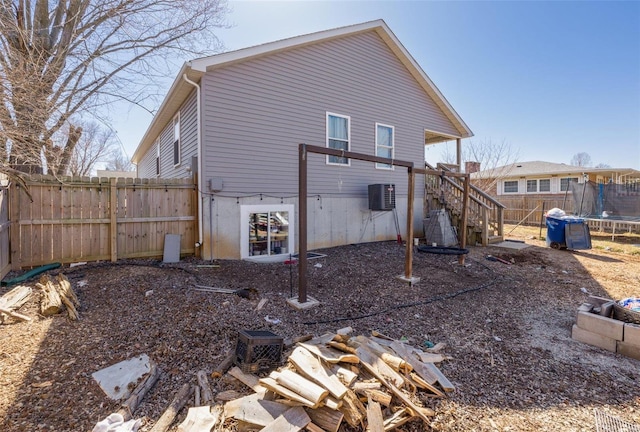 rear view of property with a trampoline, central AC, a fenced backyard, and stairway