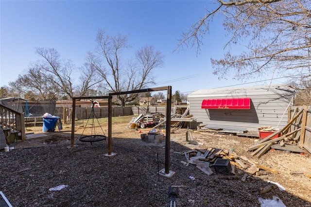 view of yard featuring an outbuilding, a trampoline, a playground, and a fenced backyard