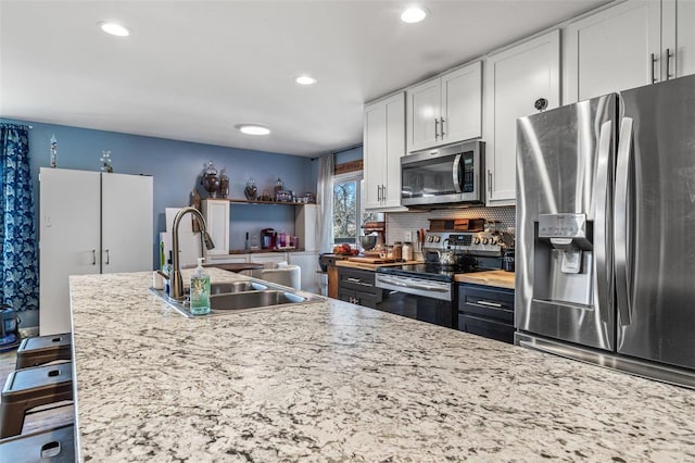 kitchen featuring white cabinets, decorative backsplash, stainless steel appliances, a sink, and recessed lighting