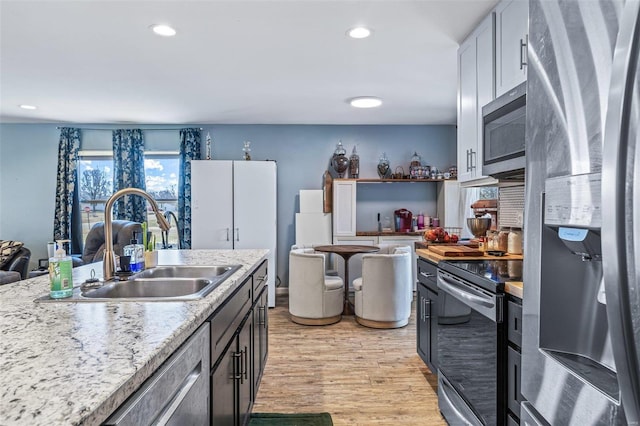 kitchen with appliances with stainless steel finishes, light wood-style floors, a sink, and recessed lighting