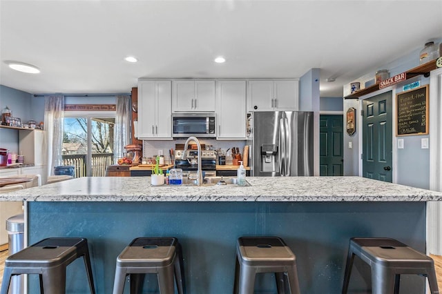 kitchen featuring stainless steel appliances, a sink, light countertops, and white cabinets