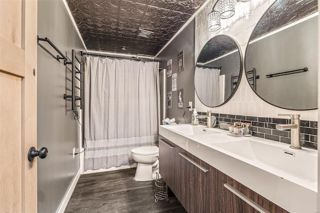 bathroom featuring decorative backsplash, toilet, an ornate ceiling, wood finished floors, and a sink