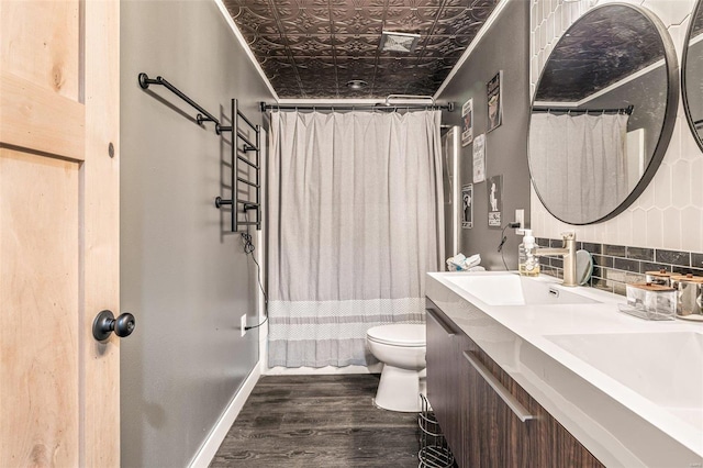 bathroom with an ornate ceiling, backsplash, a sink, wood finished floors, and baseboards