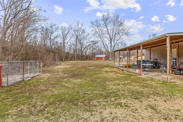 view of yard with a carport, an outbuilding, an outdoor structure, and fence