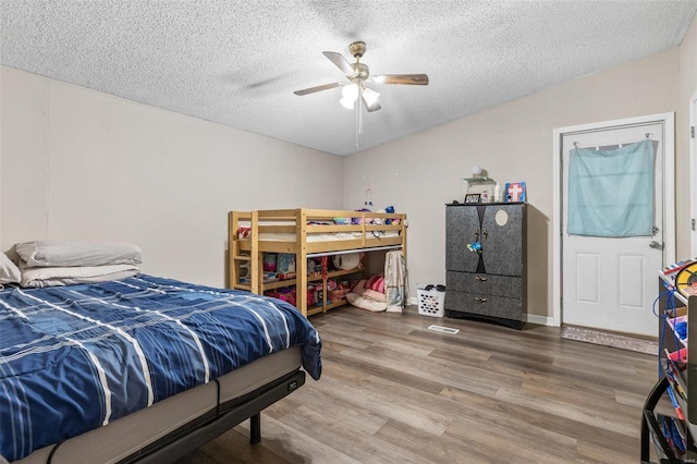 bedroom featuring a ceiling fan, vaulted ceiling, a textured ceiling, and wood finished floors