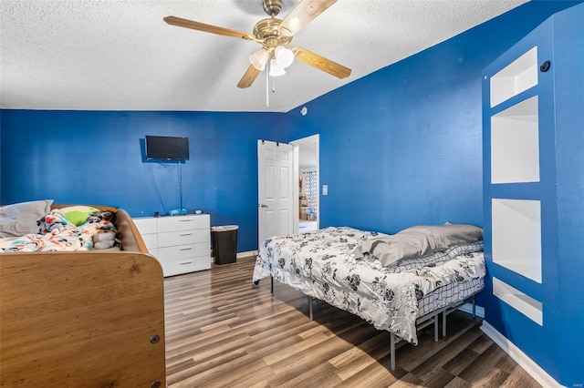 bedroom featuring a textured ceiling, wood finished floors, a ceiling fan, and baseboards