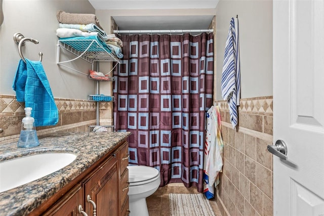 bathroom featuring tile patterned flooring, toilet, a shower with shower curtain, vanity, and tile walls