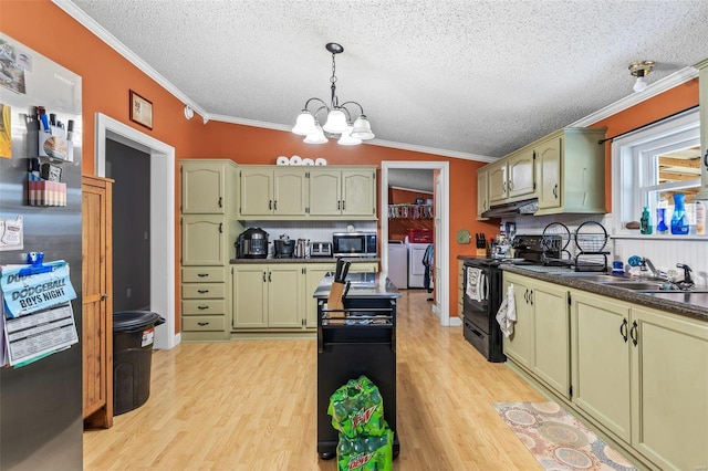 kitchen featuring under cabinet range hood, stainless steel appliances, ornamental molding, washing machine and clothes dryer, and green cabinetry