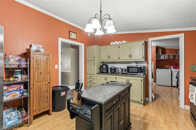 kitchen featuring separate washer and dryer, ornamental molding, light wood-type flooring, stainless steel microwave, and dark countertops