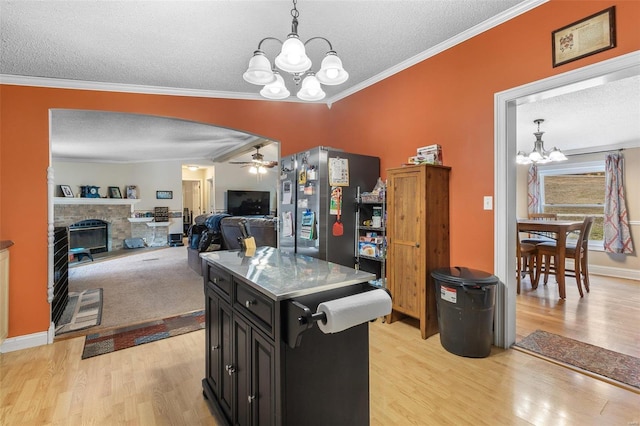 kitchen with crown molding, a fireplace, arched walkways, and dark cabinetry