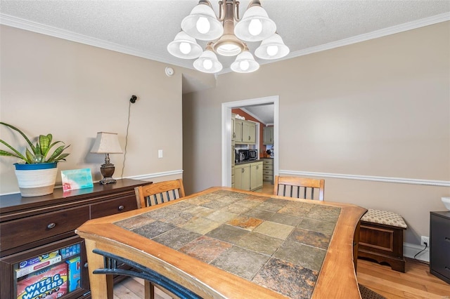 dining space with ornamental molding, a textured ceiling, and wood finished floors