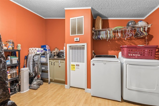 laundry area with laundry area, visible vents, wood finished floors, independent washer and dryer, and crown molding