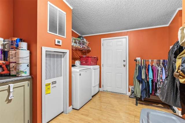 clothes washing area featuring light wood-type flooring, a heating unit, separate washer and dryer, and crown molding