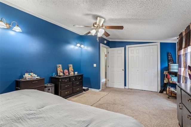 carpeted bedroom with a textured ceiling, ceiling fan, a closet, and baseboards